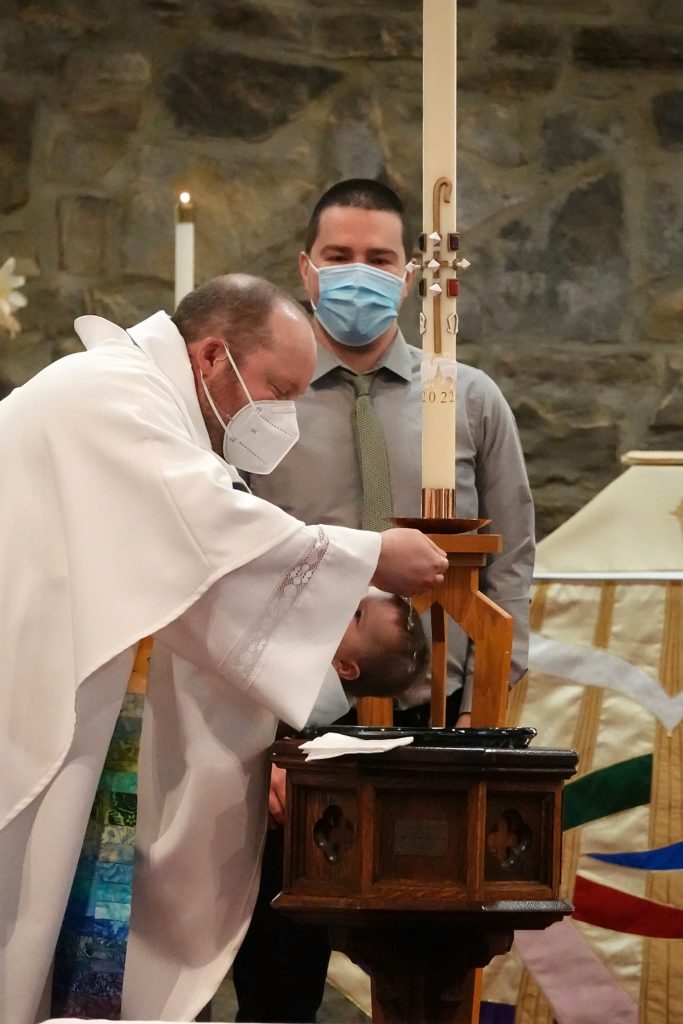 Canon Matthew baptizes a child in Easter of 2022.