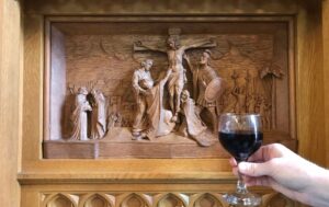 A cup of red wine is held up to the right panel of the chapel's reredos, which depicts Christ's crucifixion.