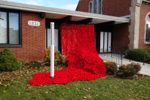Poppies flow down from the eaves of the front porch of the Nativity, coming to a pool around the base of our Peace Pole.